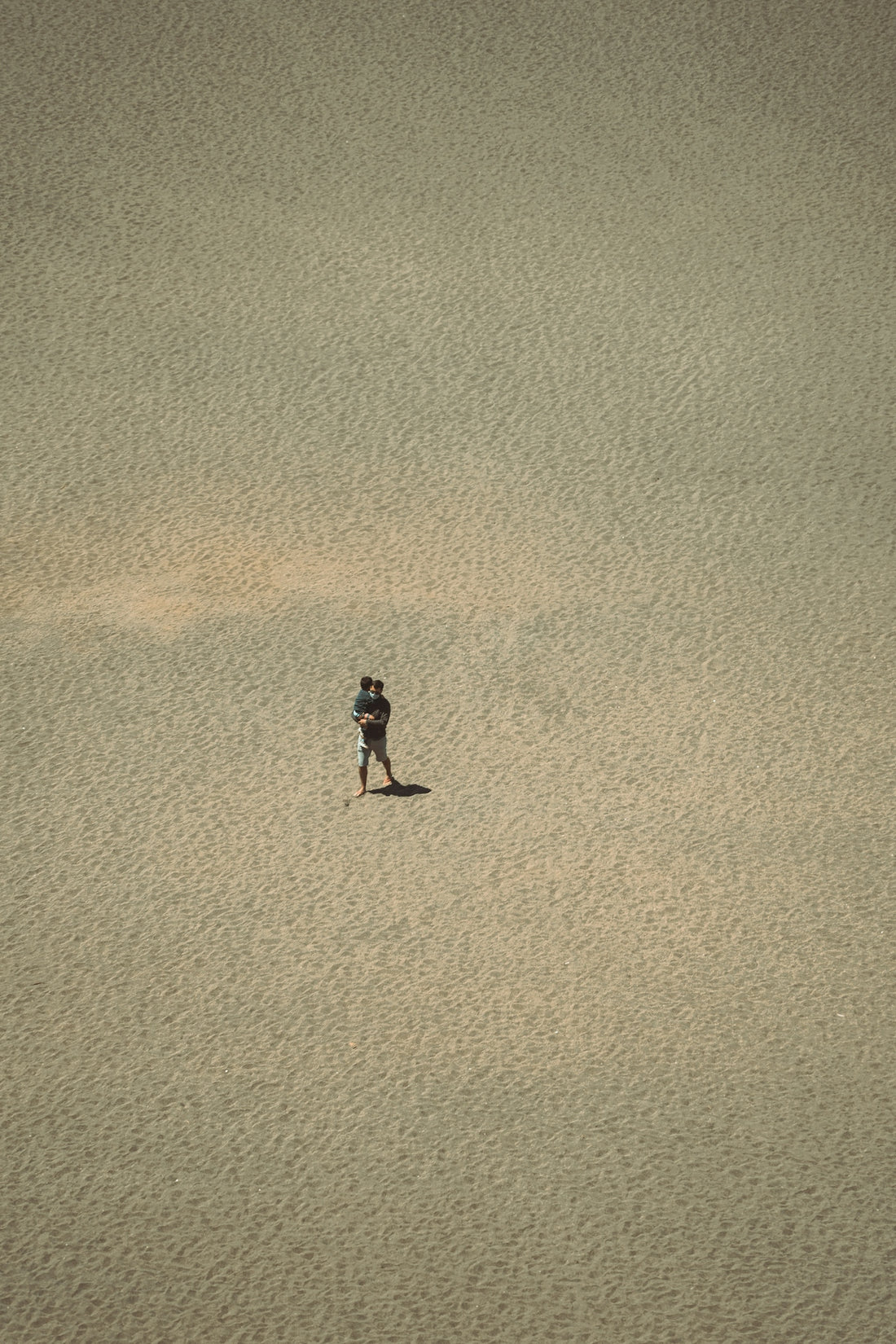 woman in black dress walking on brown sand