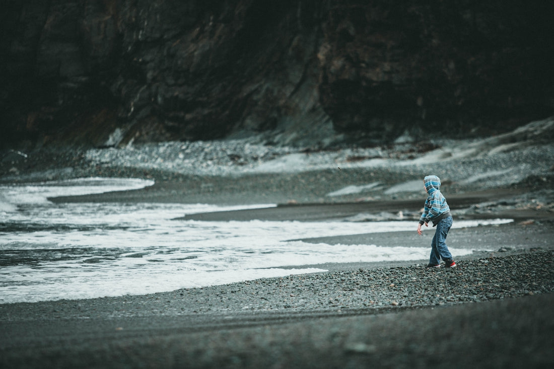 girl in blue jacket walking on beach during daytime