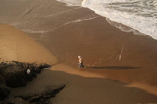 a man standing on top of a sandy beach next to the ocean