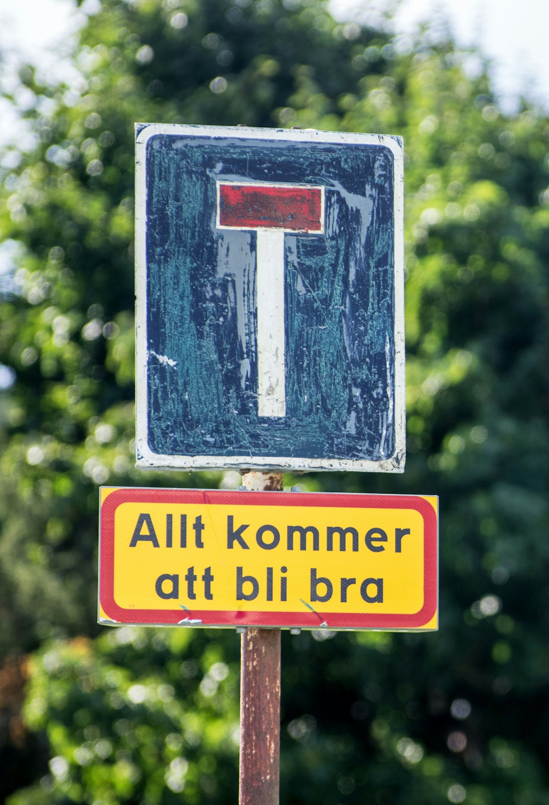 a yellow and red street sign sitting on top of a wooden pole