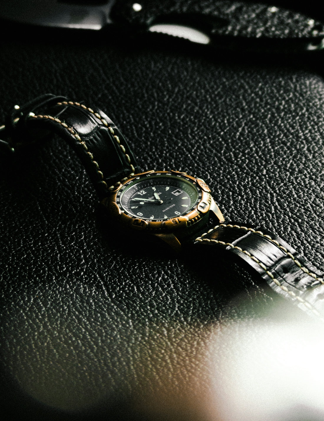 a watch sitting on a black leather surface