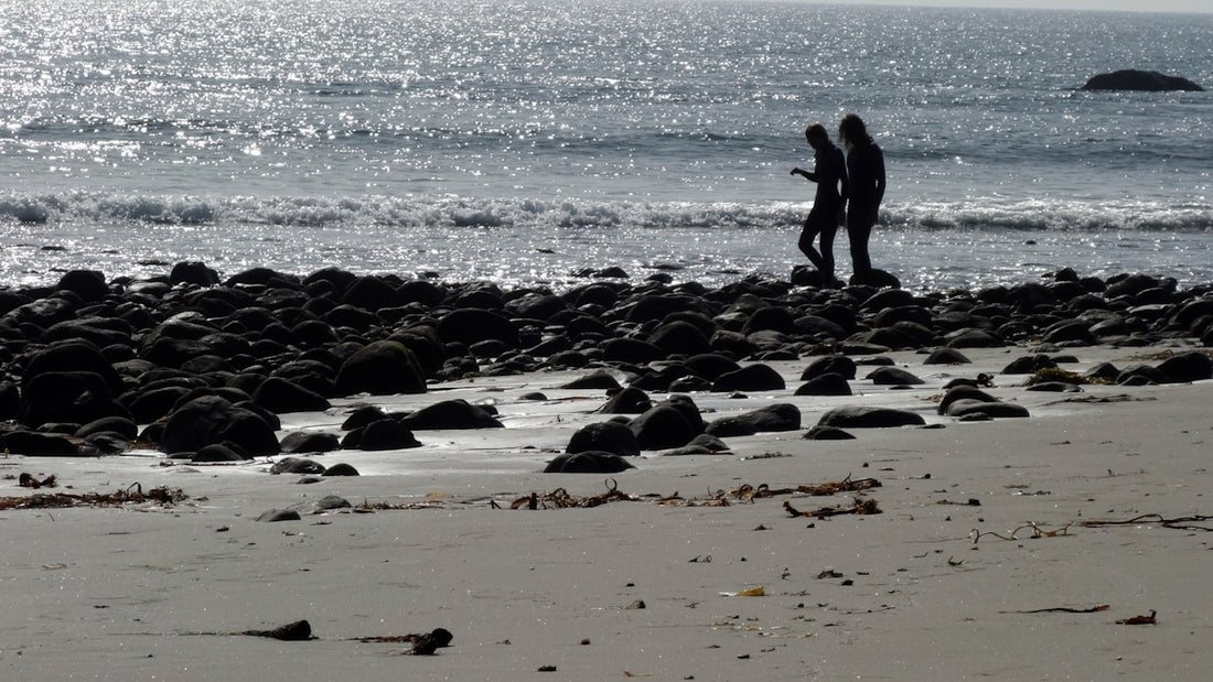 a couple of people standing on top of a sandy beach