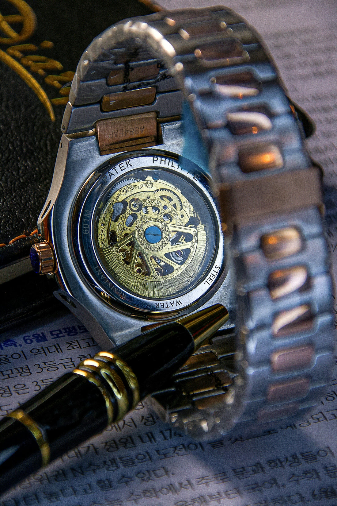 A wristwatch, pen, and paperwork are artfully arranged.
