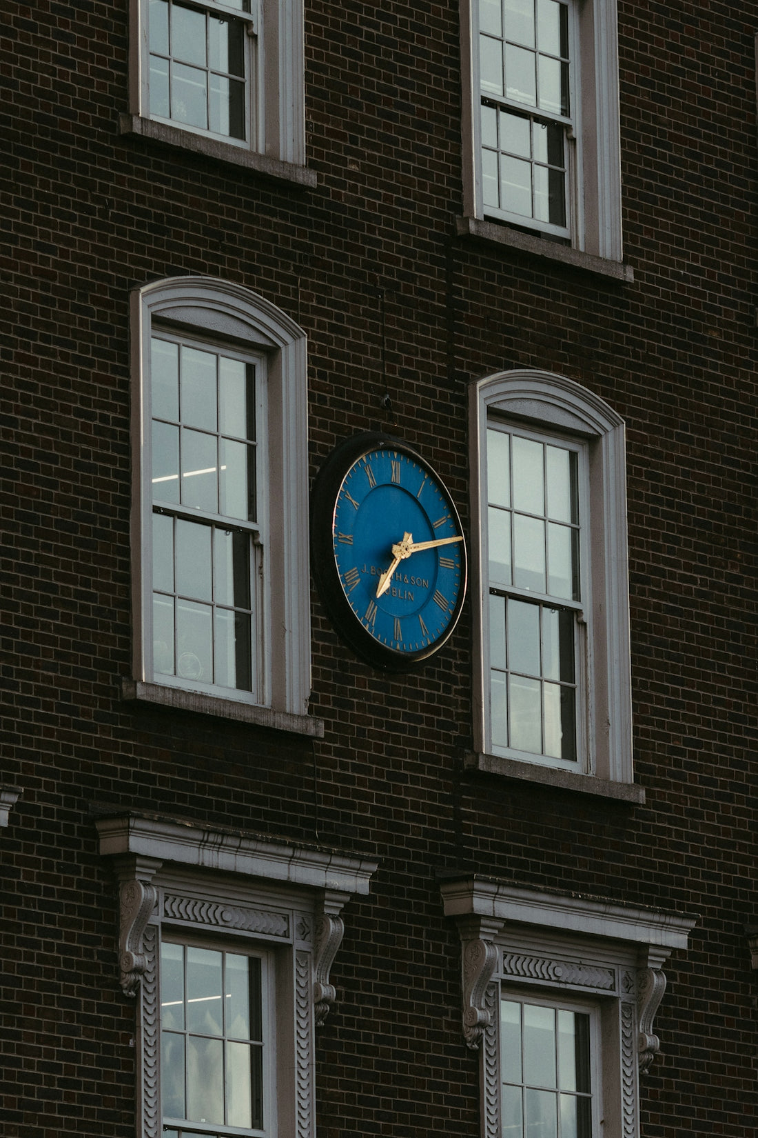 A blue clock mounted on a brick building